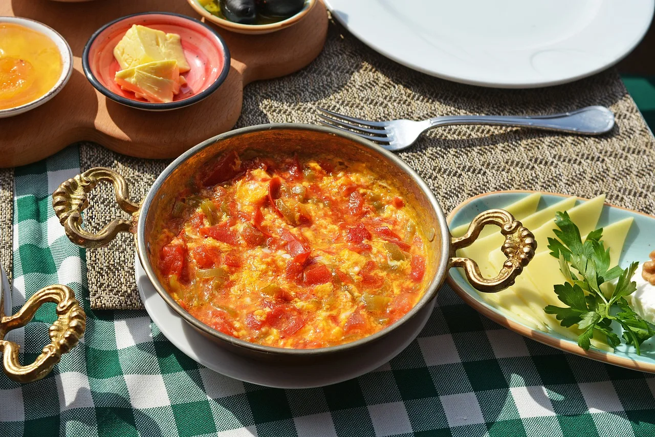 Una padella tradizionale turca con il menemen appena preparato, un piatto a base di uova, pomodori e peperoni verdi, servito con pane croccante.