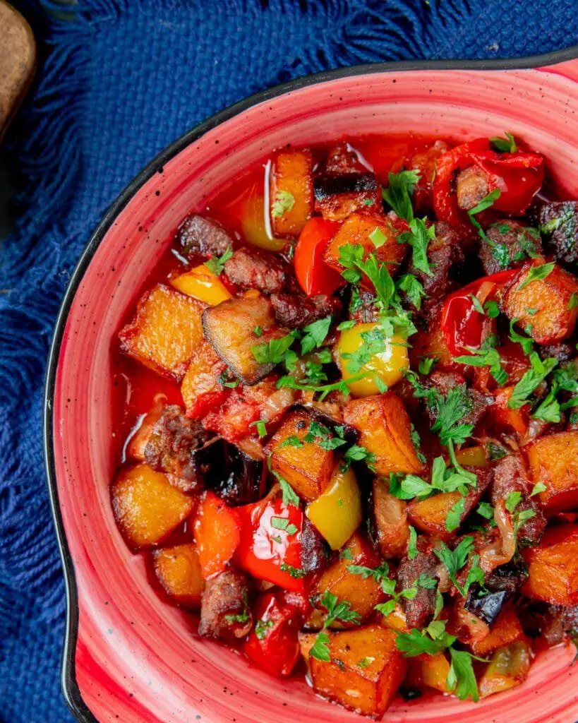 Saksuka Turca: Ricetta, Ingredienti, Varianti e Consigli 3 Saksuka turca servita in modo rustico, con cubetti di melanzane, peperoni e pomodori cotti, decorata con prezzemolo fresco appena raccolto.