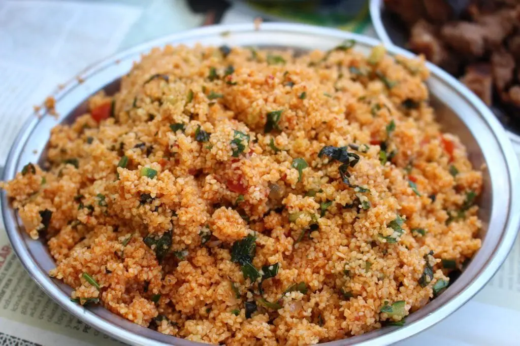 Kisir: Piatto Turco Con Bulgur e Verdure di Stagione 4 Primo piano di una ciotola piena di kisir appena preparato, con bulgur fine, erbe fresche e pomodoro, dal colore vivace e consistenza granulosa.