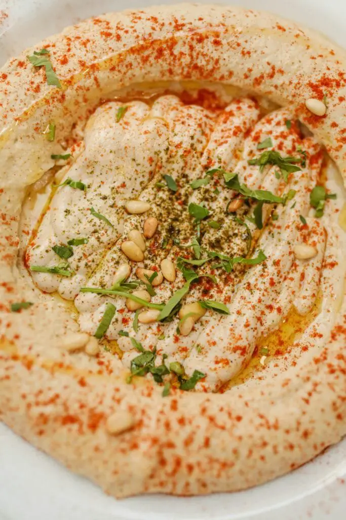 Hummus di Ceci Fatto in Casa: Ricetta Facile e Cremosa 4 Hummus di ceci decorato con paprika, pinoli tostati ed erbe fresche, condito con olio extravergine d'oliva
