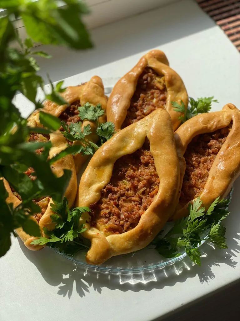 Pide Turca con Peperoni e Pomodori: Ricetta E Varianti 1 Pide turche fatte in casa con ripieno di peperoni e pomodori, servite su un piatto di vetro con prezzemolo fresco